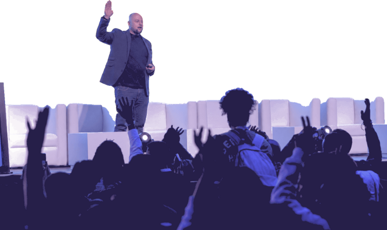 Francois van der Merwe speaking on stage, one hand raised, to a crowd with hands up in response